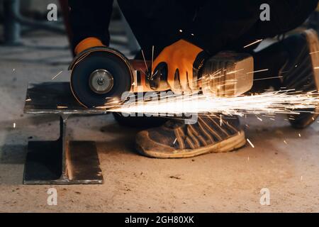 Male worker cutting metal using electric saw while working at construction site Stock Photo