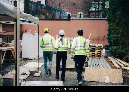Rear view of male and female engineers walking at construction site Stock Photo