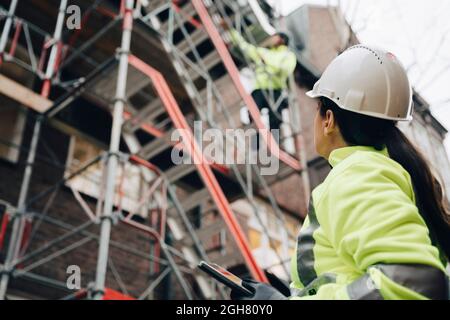 Female building contractor wearing hardhat examining construction site Stock Photo