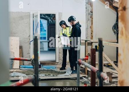 Female engineer discussing with male construction worker at site Stock Photo