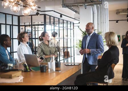 Male investor presenting ideas with hackers at startup company Stock Photo