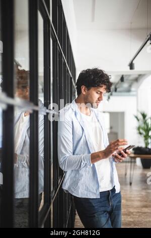Young businessman using smart phone in office Stock Photo
