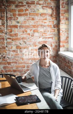 High angle portrait of female hacker sitting on chair at startup company Stock Photo