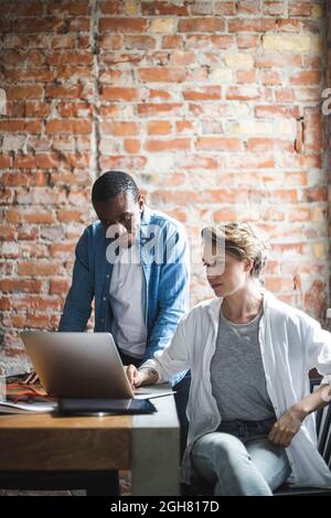 Male and female colleagues using laptop in office Stock Photo