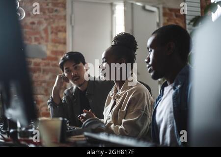 Female hacker discussing with male colleague over computer in creative office Stock Photo