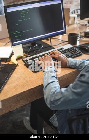 Midsection of male hacker coding on computer at office Stock Photo