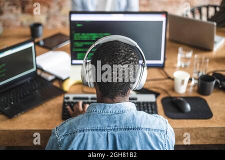 Rear view of male programmer working on computer at startup company Stock Photo