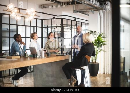 Mature male investor presenting ideas with programmers at office Stock Photo