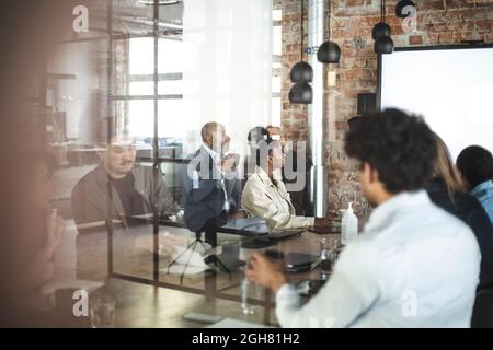 Male and female professionals discussing over presentation at office Stock Photo