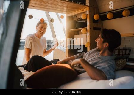 Happy male friends talking with each other in camping van Stock Photo