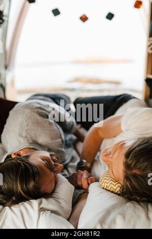 Male friends lying on side at camping van during vacation Stock Photo