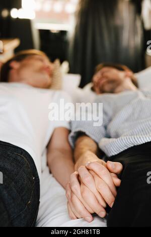 Gay couple holding hands while lying down in motor home during vacation Stock Photo