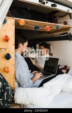 Man using laptop sitting with boyfriend in motor home Stock Photo