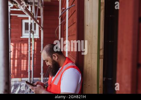 Bearded male construction worker using smart phone at site Stock Photo