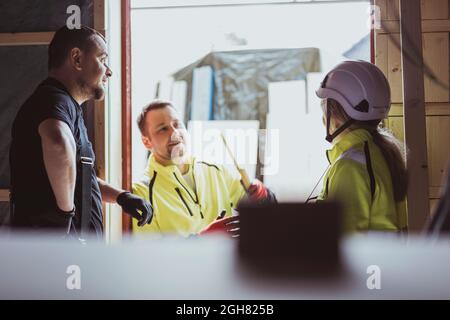 Male and female construction workers discussing together at construction site Stock Photo