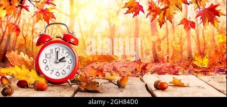 Fall Back Time - Daylight Savings End - Clock Alarm And Leaves In Autumn Background Stock Photo