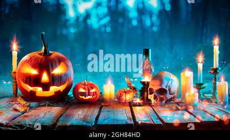 Halloween At Night - Jack O Lantern On Table With Candles In Forest Stock Photo