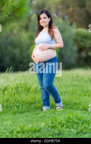 Vertical photo of a pregnant woman walking in a park Stock Photo