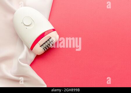 White epilator on soft silk. Hair removal and depilatory concept Stock Photo
