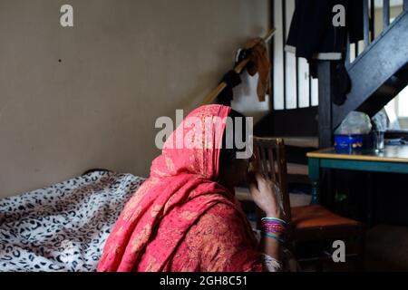 Pakistani Woman Immigrant, Sitting on bed, at home, Rugby, England, UK Stock Photo