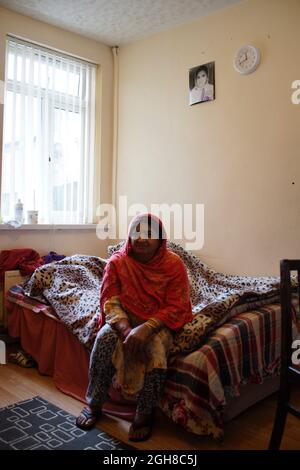 Pakistani Woman Immigrant, Sitting on bed, at home, Rugby, England, UK Stock Photo