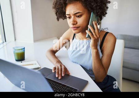 Focused curly-haired woman making a phone call Stock Photo