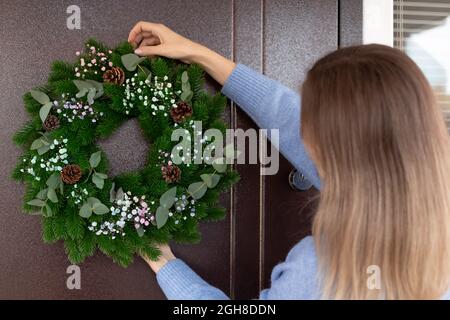 woman hanging Christmas wreath on front door Stock Photo