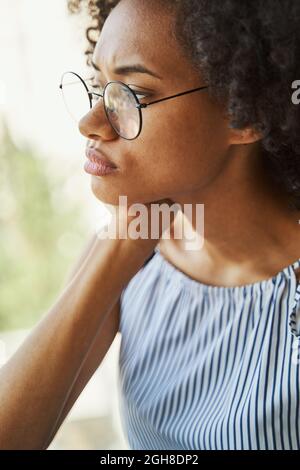 Low-spirited female in trendy circle eyeglasses staring into the distance Stock Photo