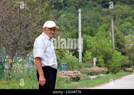 Elderly man standing on rural street. Concept of life in village, old age Stock Photo