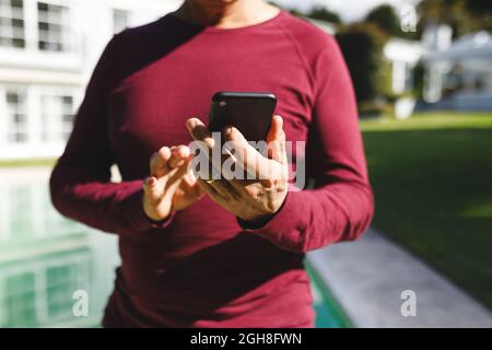 Mid section of senior caucasian man using smartphone in sunny garden Stock Photo