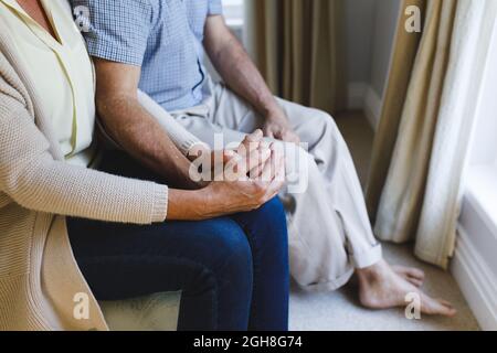 Senior caucasian couple sitting on sofa and holding hands Stock Photo