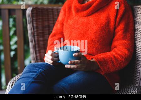 Midsection of senior caucasian woman sitting on chair, holding cup in garden Stock Photo