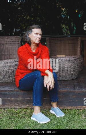 Thoughtful senior caucasian woman sitting and looking away in garden Stock Photo