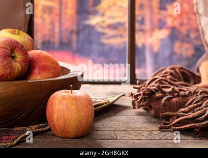 Fresh red apples on a wooden table by a window with autmn background Stock Photo
