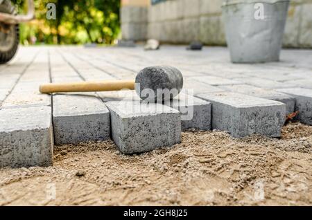 Hammer for sealing the pavement on the newly laid pavement. process of laying paving stones. Stock Photo