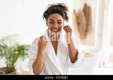 Happy Black Woman Flossing Teeth Smiling To Camera In Bathroom Stock Photo