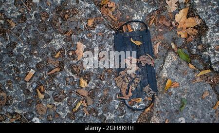 Close-up of a used medical mask thrown on the sidewalk. Concept of recycling, pollution and waste. Disposable hygienic discarded face mask Stock Photo