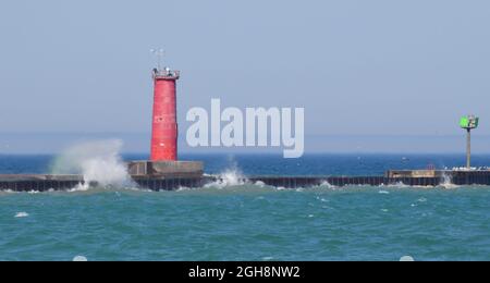 Waves crashing against red lighthouse along the water pier Stock Photo