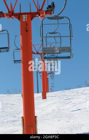 Bright orange empty chair lifts at a ski resort on a sunny day Stock Photo