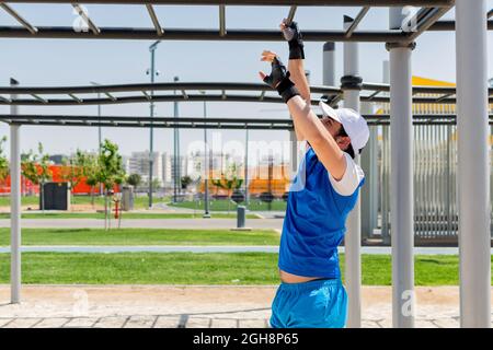Muscular man hanging on bar and performing calisthenics pull up ...