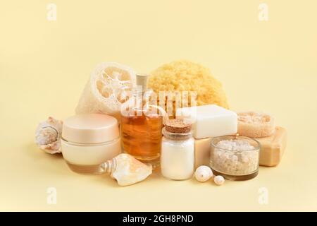 Natural cosmetics and bath accessories: bath salt, cream, bottles of essential oils, soap, sea sponge on a yellow pastel background. Spa concept. Spac Stock Photo