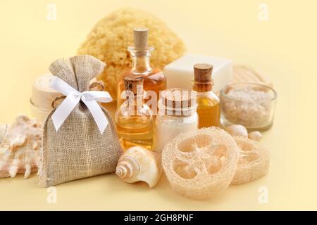 Natural cosmetics and bath accessories: bath salt, cream, bottles of essential oils, soap, sea sponge on a yellow pastel background. Spa concept. Stock Photo