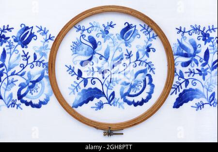 Embroidery hoop with fabric, top view. Blue floral ornament on a white background Stock Photo