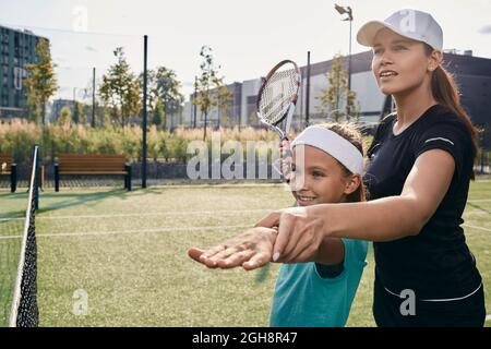 Female tennis coach teaches little girl to play tennis on grass court. tennis lesson for a child Stock Photo