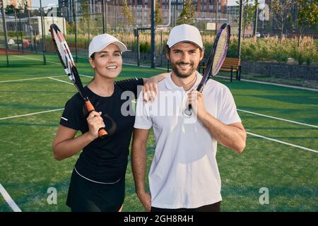 Beautiful couple of tennis players happy after playing tennis outdoors Stock Photo