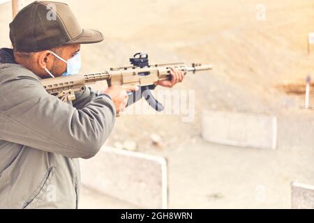 Men practicing shooting with a assault rifle at target. Selective Focus Stock Photo