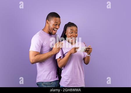Portrait of surprised black couple using smartphone Stock Photo