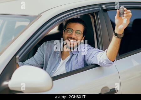 Cheerful indian long-haired guy showing car key and smiling Stock Photo