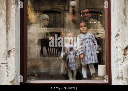 LVIV, UKRAINE - September 6, 2021. Arabic Happy Family drink coffe. People sit inside the cafe in Lviv, Ukraine. Photo through the window Stock Photo