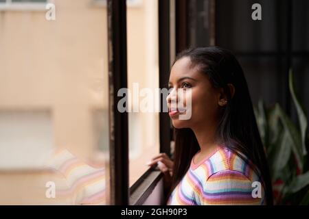 Smiling African American girl near the window looking out.